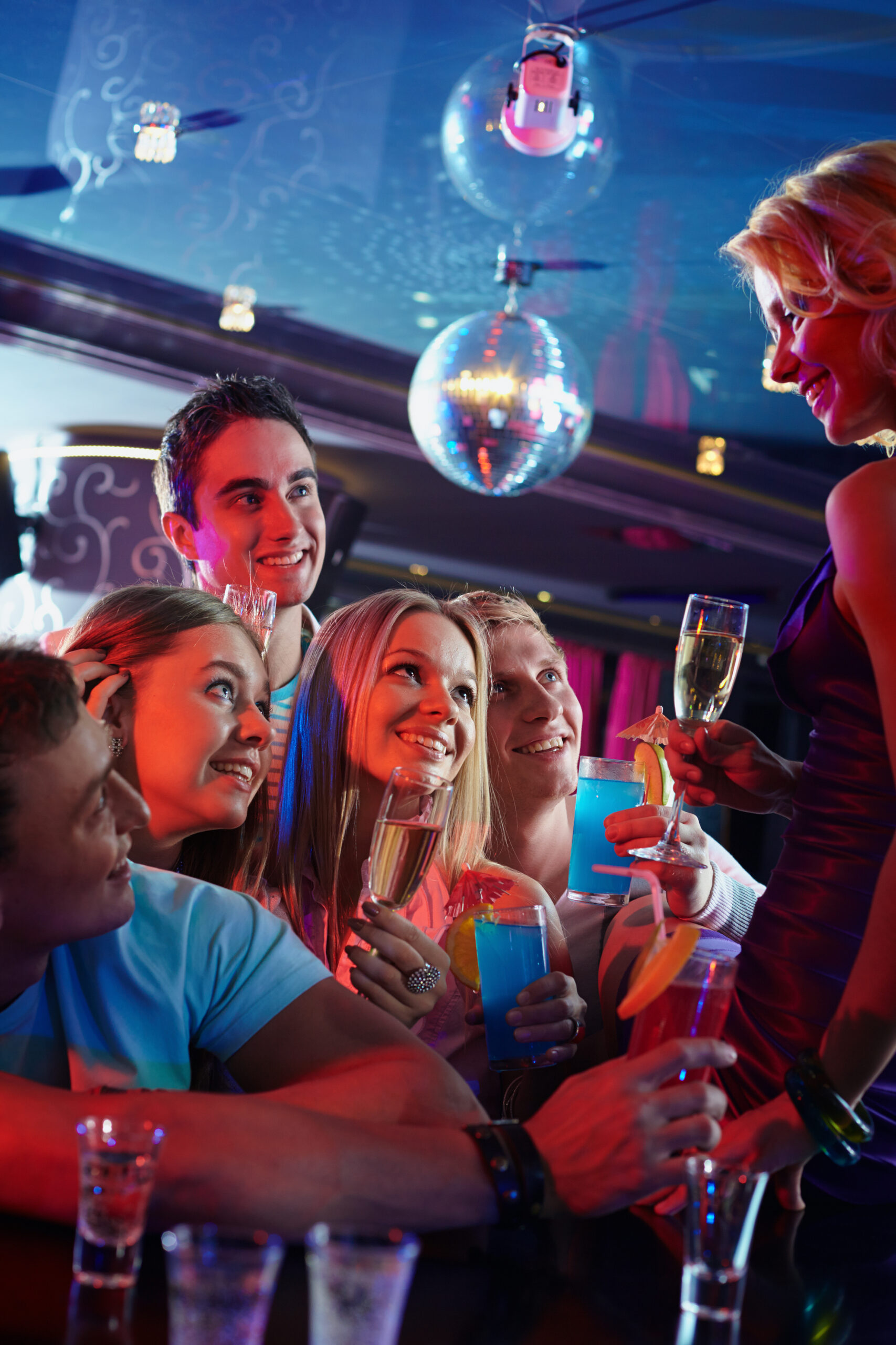 Portrait of happy friends with alcohol looking at attractive girl with glass of champagne in the bar